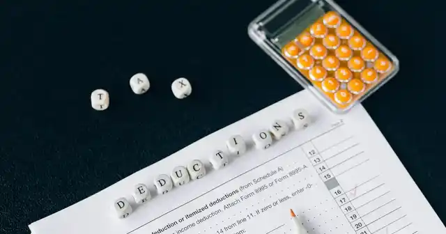 Calculadora y formulario de impuestos con dados que forman la palabra deducciones
